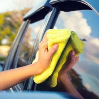 Hand wiping down car window with microfiber cloth